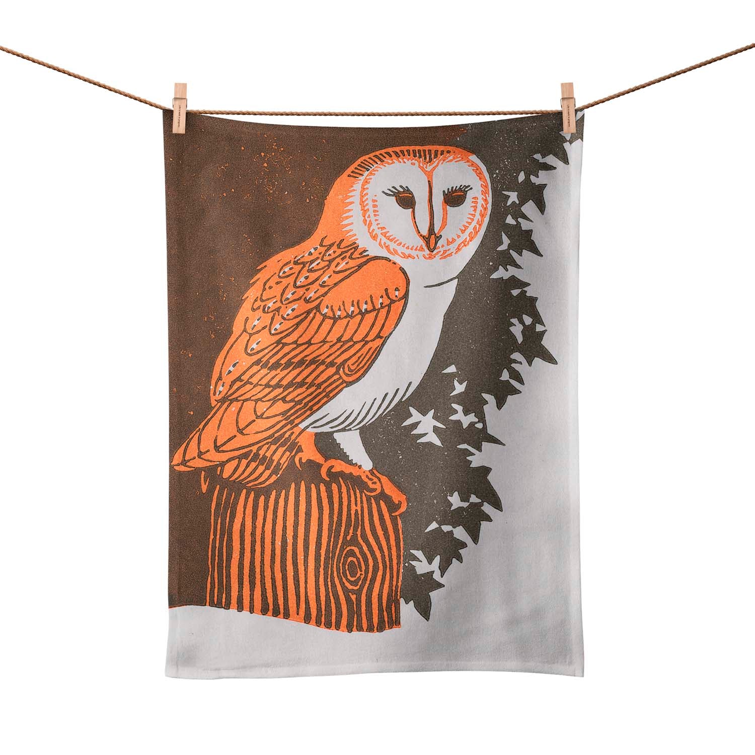 A tea towel with a barn owl on.  The tea towel is pegged on a line. 